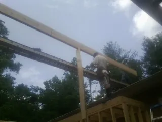 Carpenter setting a ridge beam over a new addition frame — Ice Dam Removal by Roofing Brothers in Tintah
