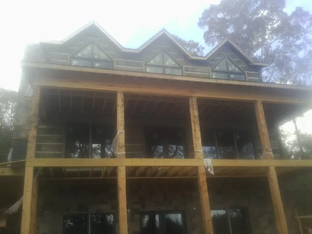 Dormers and porch framing on a large log home under construction — Roof Coating work by our crew in Tintah