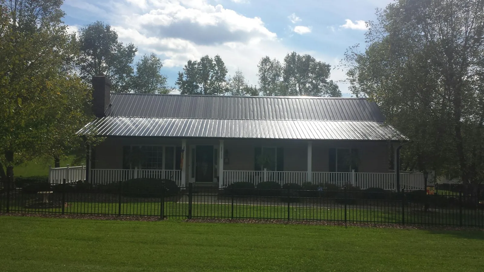 Gray metal roof on a brick ranch with a full width front porch — Gutter Guard Installation work by our crew in Tintah