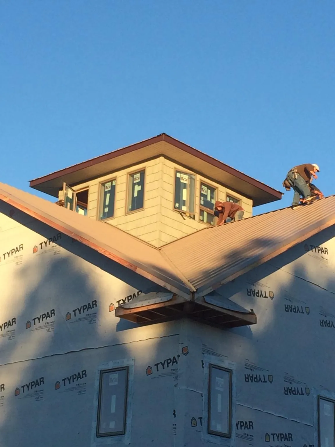 Roofers working around a rooftop cupola on a new metal roof at sunset — Roof Waterproofing in Tintah by Roofing Brothers